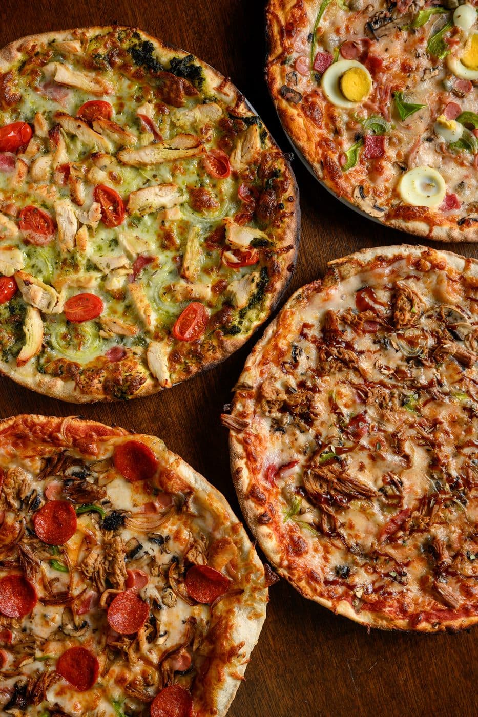 Four pizzas laid out side by side