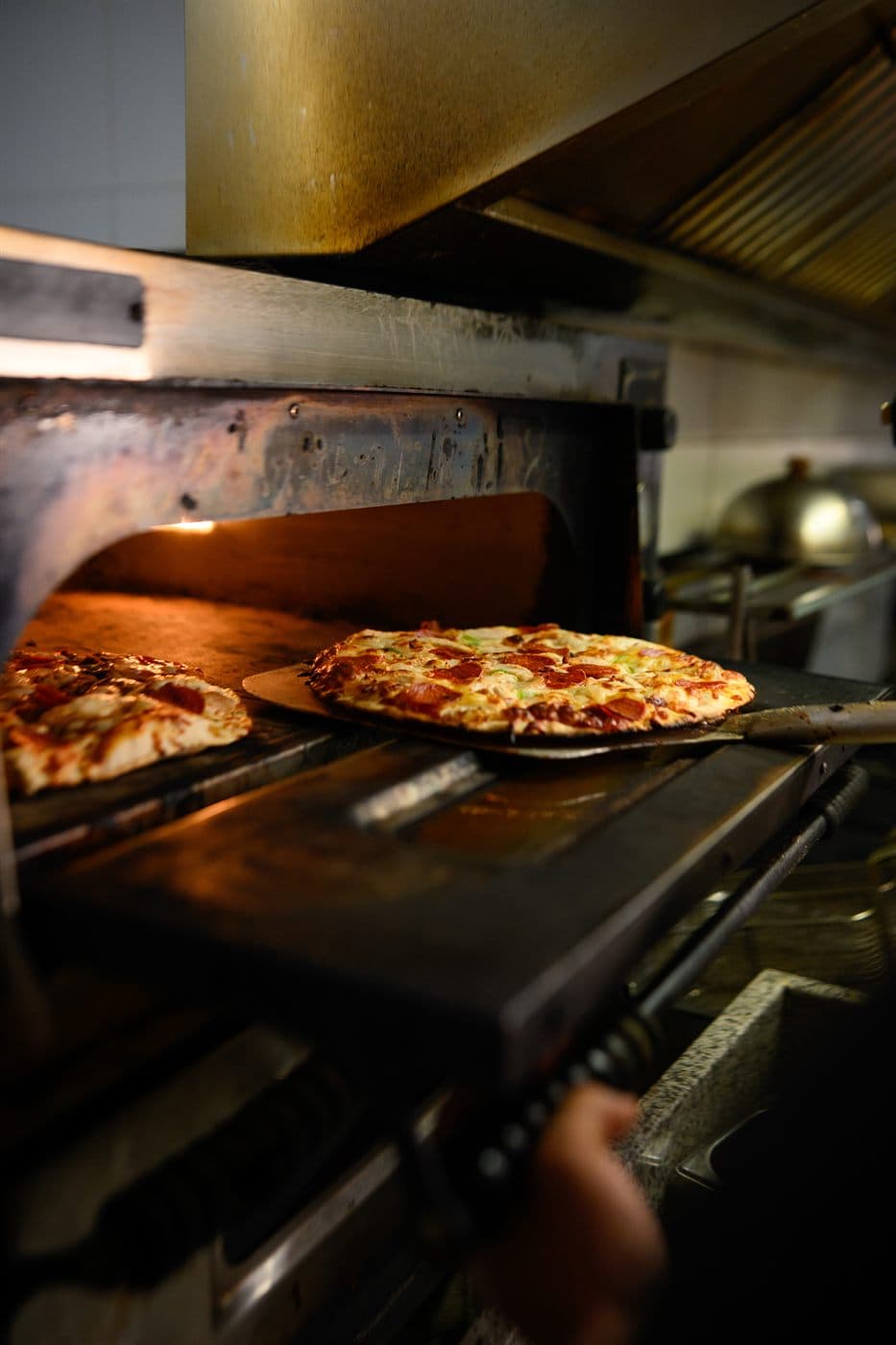 A pizza sliding off the peel into the oven