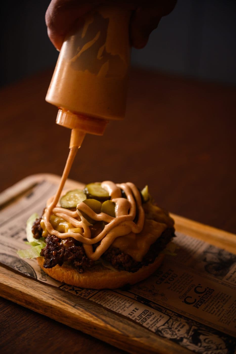 Sauce being poured over a burger