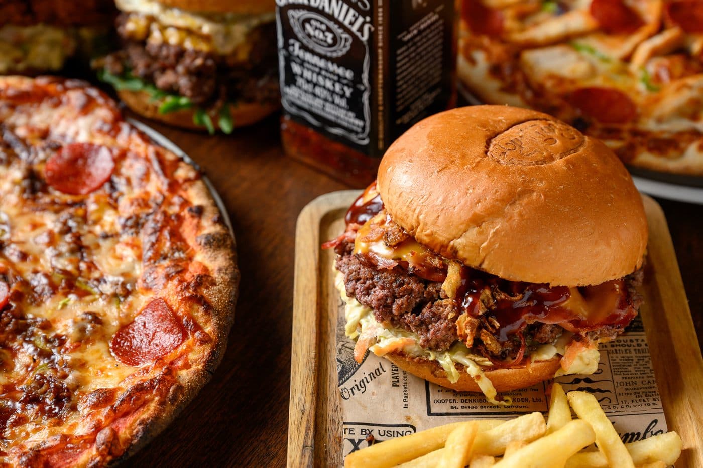 A burger in front of a pizza on the bar