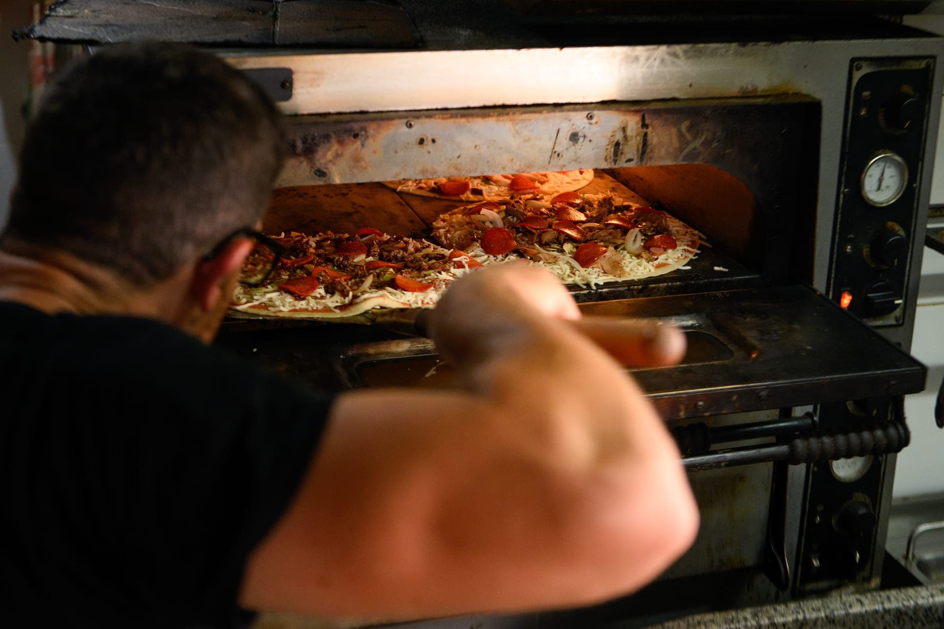 A pizza being pulled from the stone oven