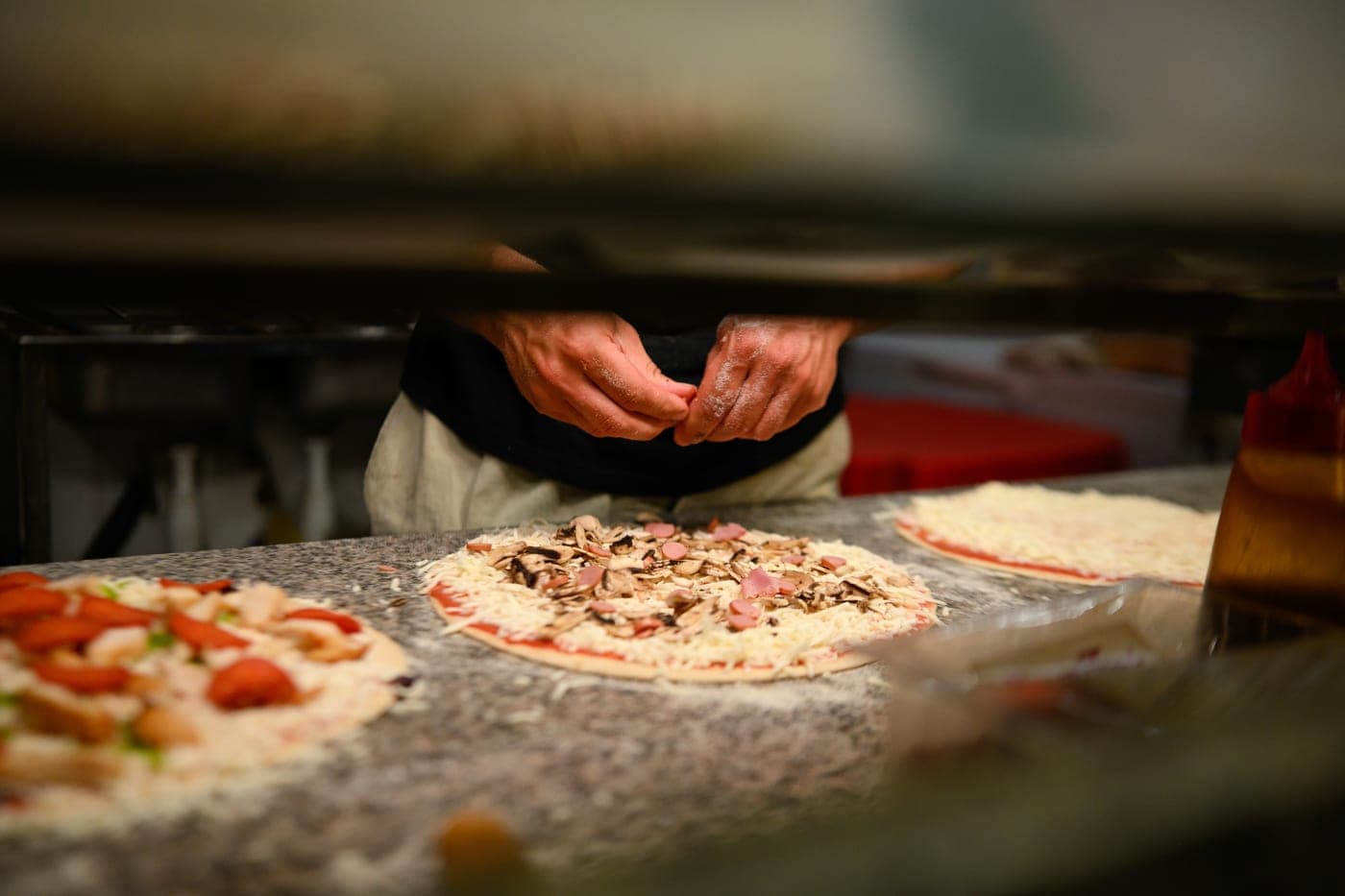 Hands stretching a pizza base on the counter